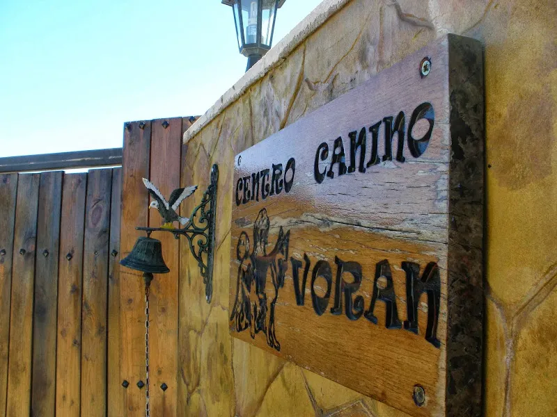 Cartel de madera en la entrada con el nombre educadores caninos voran y siluetas de perros